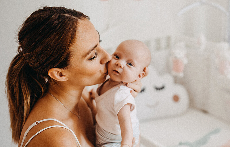 A mother kissing a newborn