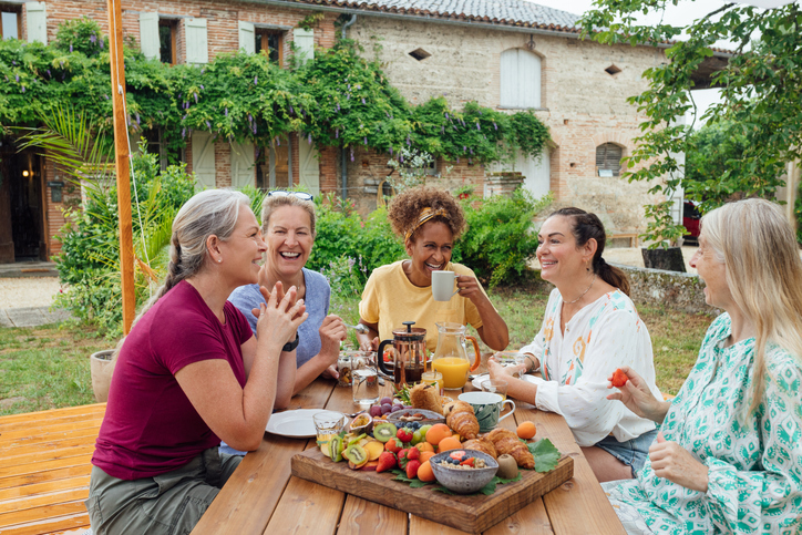 Group of women having breakfast relaxing in the morning, eating fruit and drinking coffee. They are sitting outdoors while on vacation in Montauban, Toulouse, South of France.