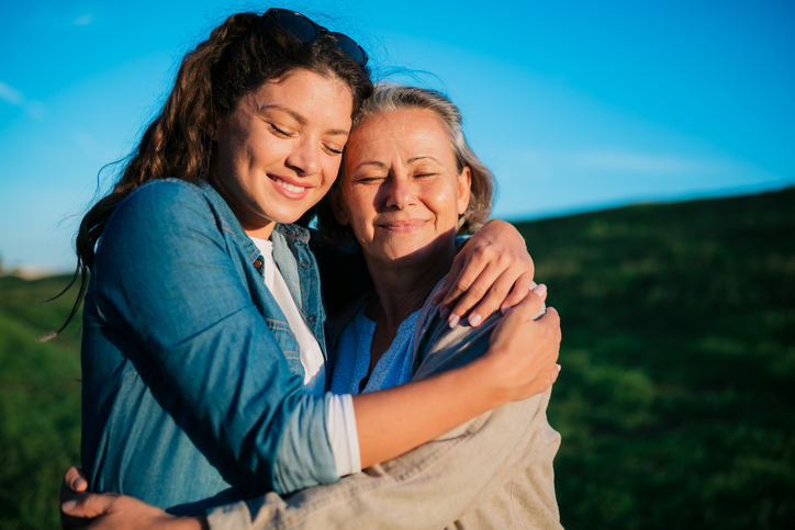 Close-up portrait of loving daughter embracing her mother outside in nature. Loving mother and daughter celebrating mother's day outdoors.