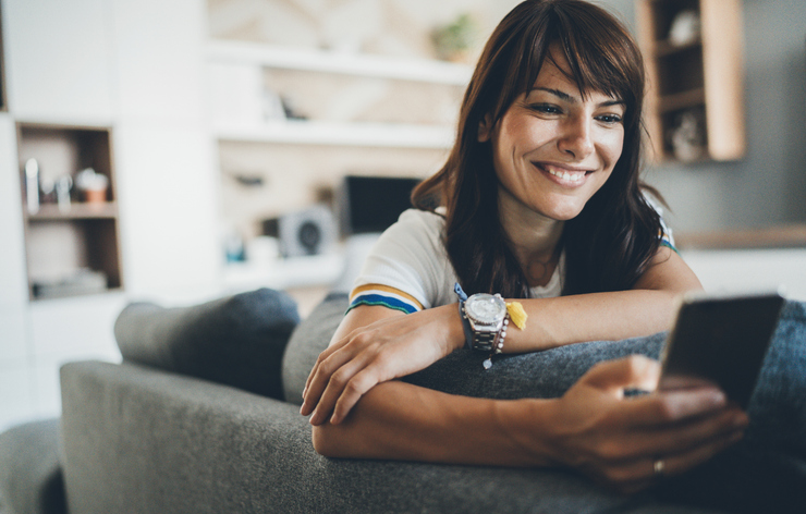 Young beautiful woman texting surfing the net on the sofa at home