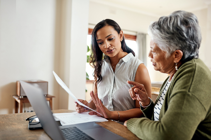 Cropped shot of an attractive young woman sitting and explaining financial documents to her grandmother in their home