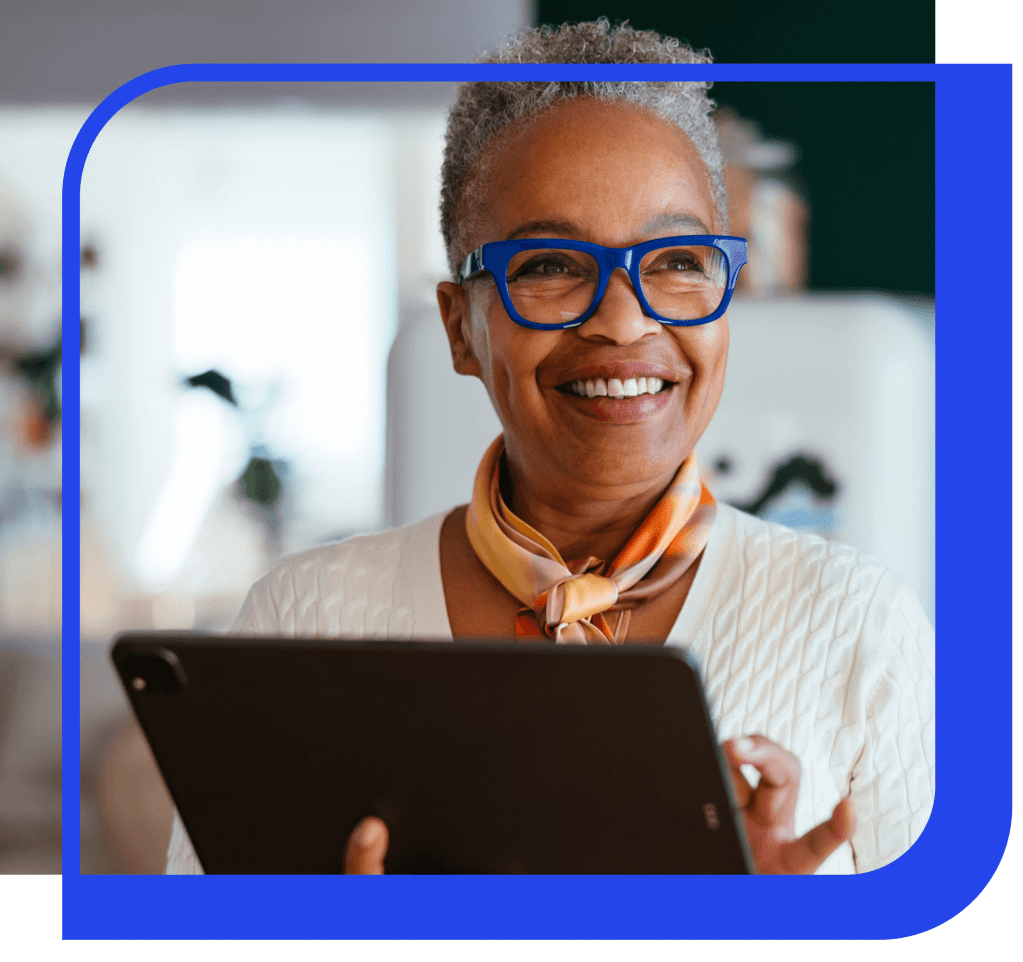 woman wearing blue glasses smiling using a tablet